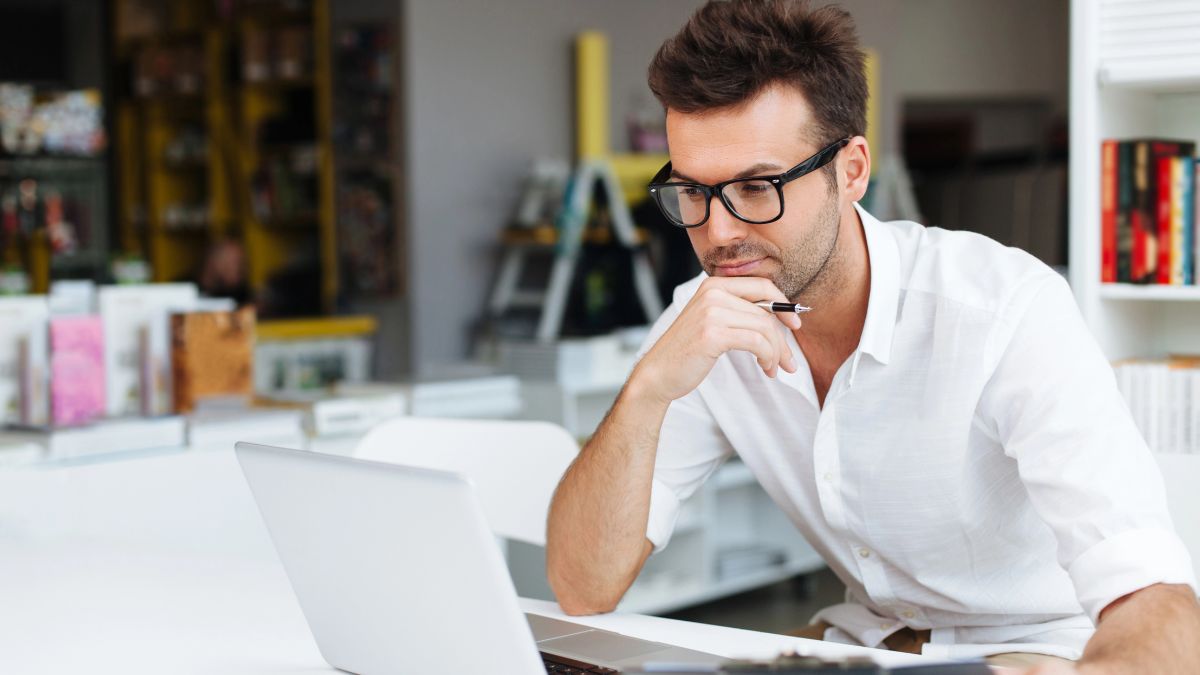 man smiling at computer hand on chin